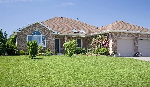 Brick house with a manicured lawn under a clear sky in Ada, MI.